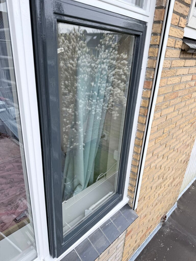 Reflectie van boom in raam met blauwe gordijnen.