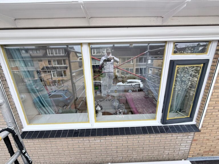 Buitenzijde huis met grote ramen en reflectie.