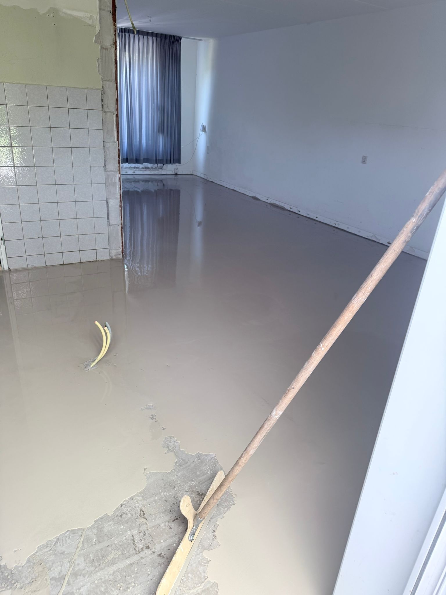 Nieuw egaliseervloer in lege kamer met gereedschap