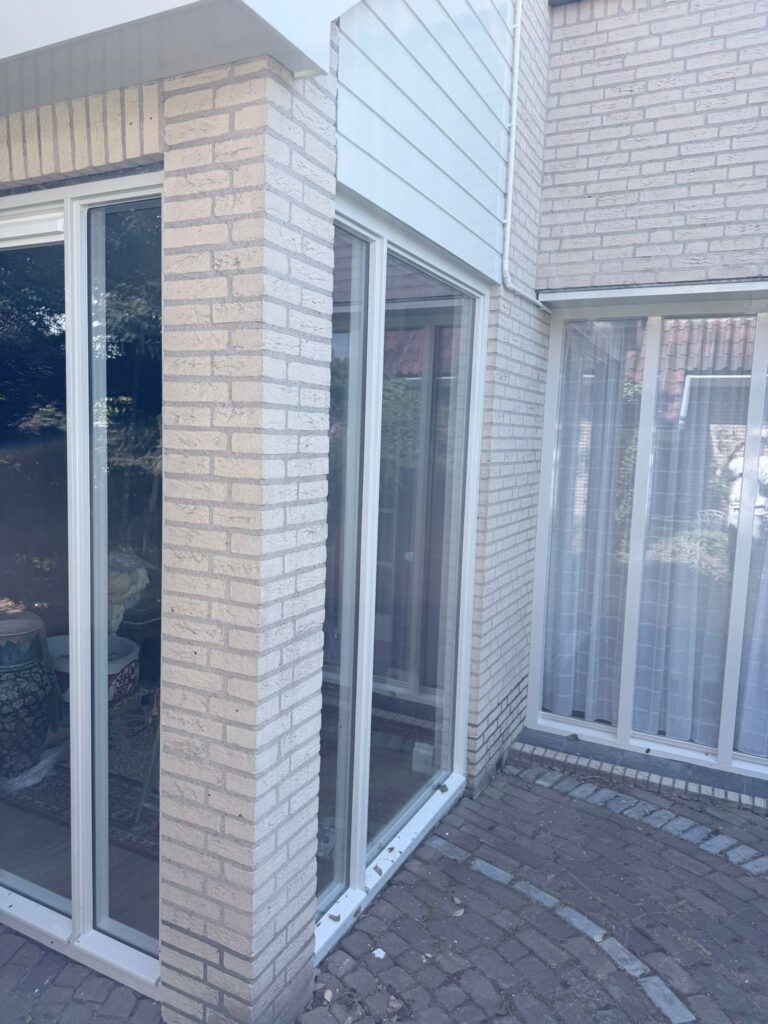Wit geschilderde kozijnen en voordeur na buitenschilderwerk en houtrotreparatie aan een woning in Egmond-Binnen