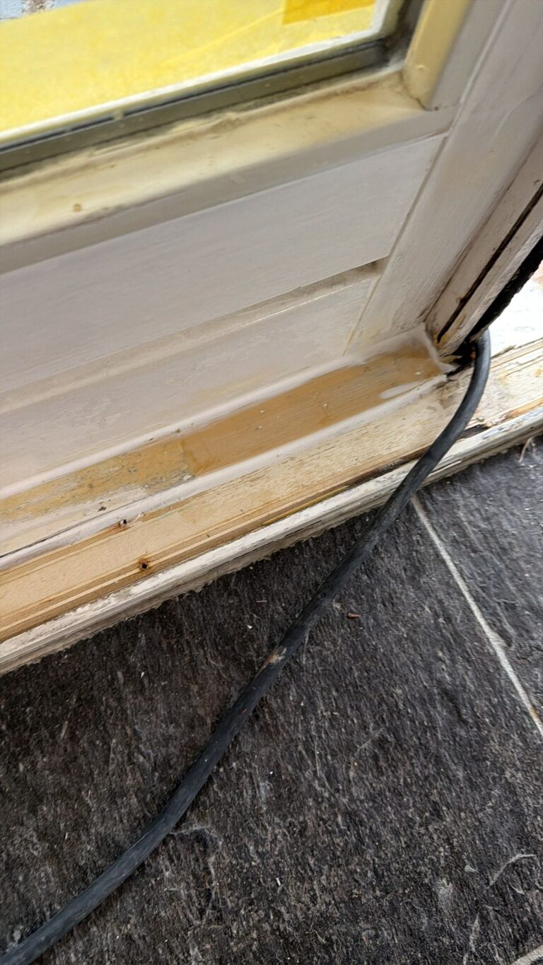 Wit geschilderde kozijnen en voordeur na buitenschilderwerk en houtrotreparatie aan een woning in Egmond-Binnen