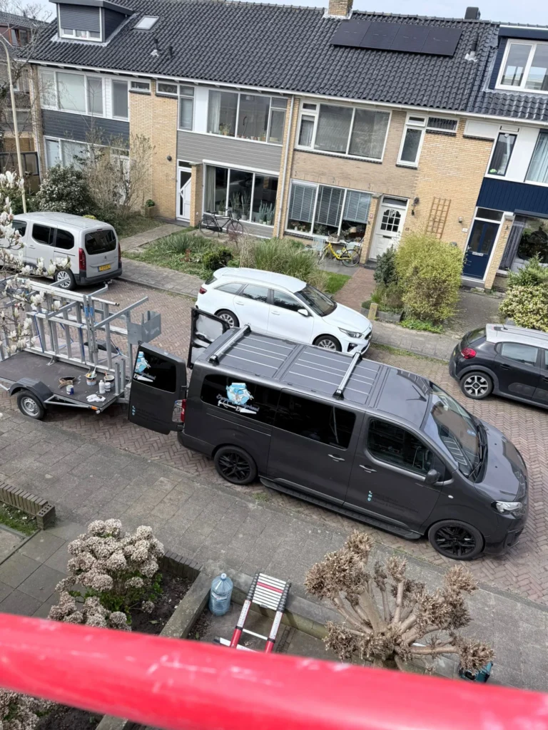 Bedrijfsbus met aanhanger en steigerdelen in een woonstraat, gezien vanaf een steiger in Castricum