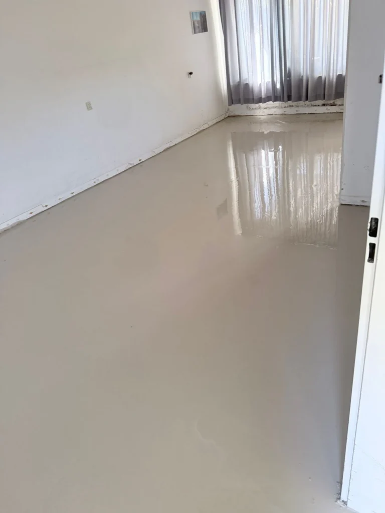 Strak geëgaliseerde, nog glanzend natte vloer in een lege kamer met witte wanden in Castricum