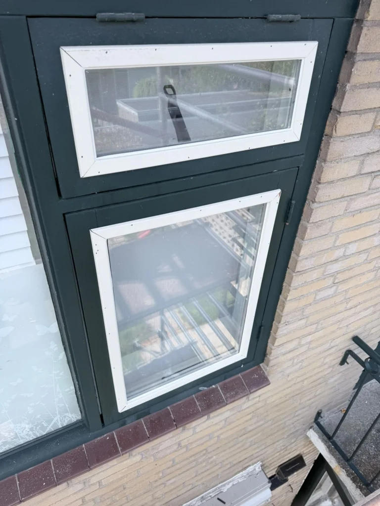 Nieuw glas met witte glaslatten in een donkergroen kozijn in een bakstenen gevel in Castricum