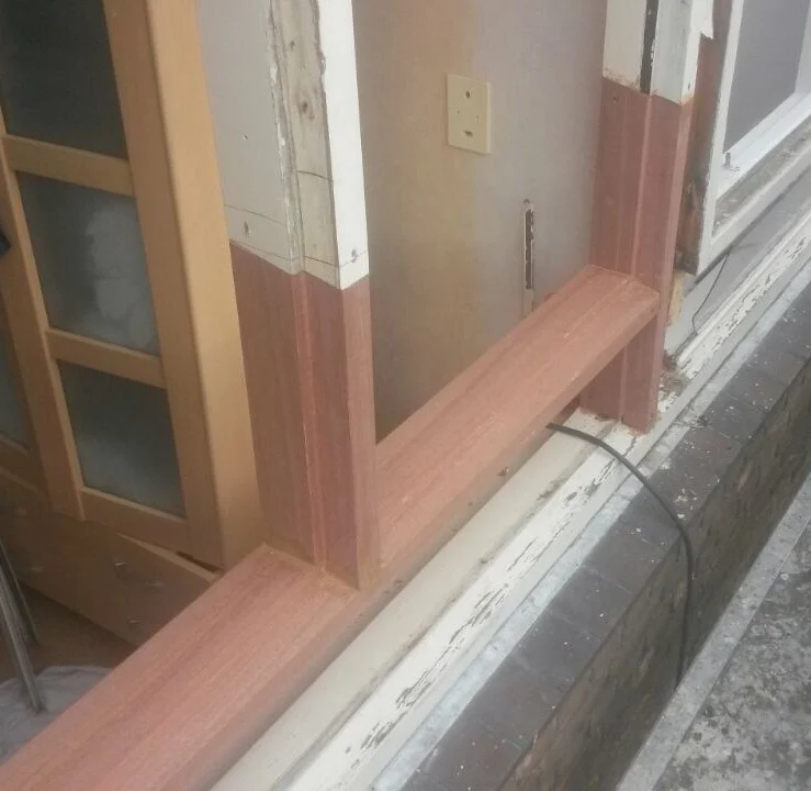 Nieuw roodbruin hout ingezet in de onderzijde van een wit kozijn in Heiloo