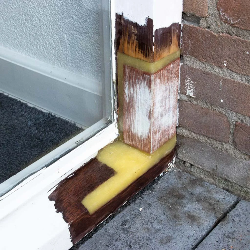 Onderkant van een kozijnstijl hersteld met een ingezet stuk hout en gele epoxy in Limmen