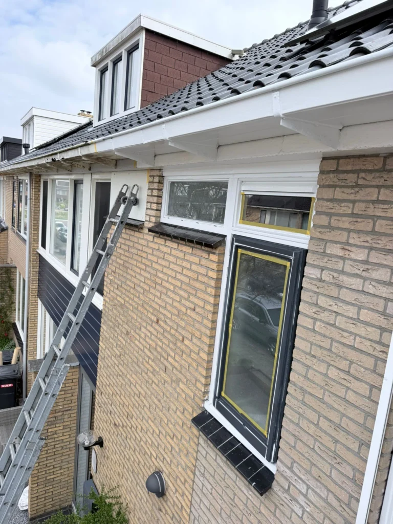 Ladder tegen de gevel van een rijtjeshuis met afgeplakt raam en wit dakoverstek in Castricum