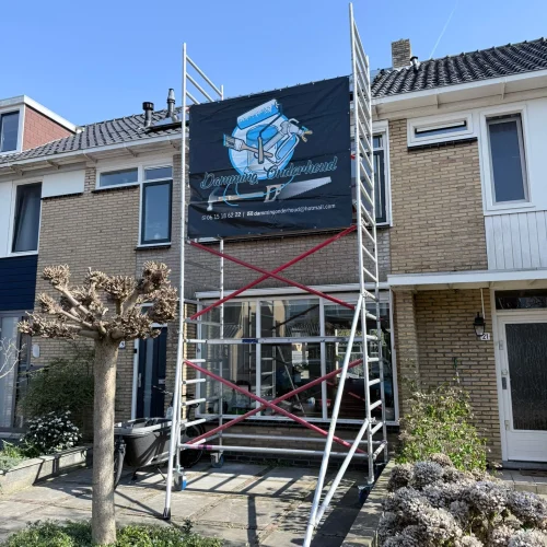 Rolsteiger met bedrijfsspandoek voor de gevel van een rijtjeshuis in Heiloo